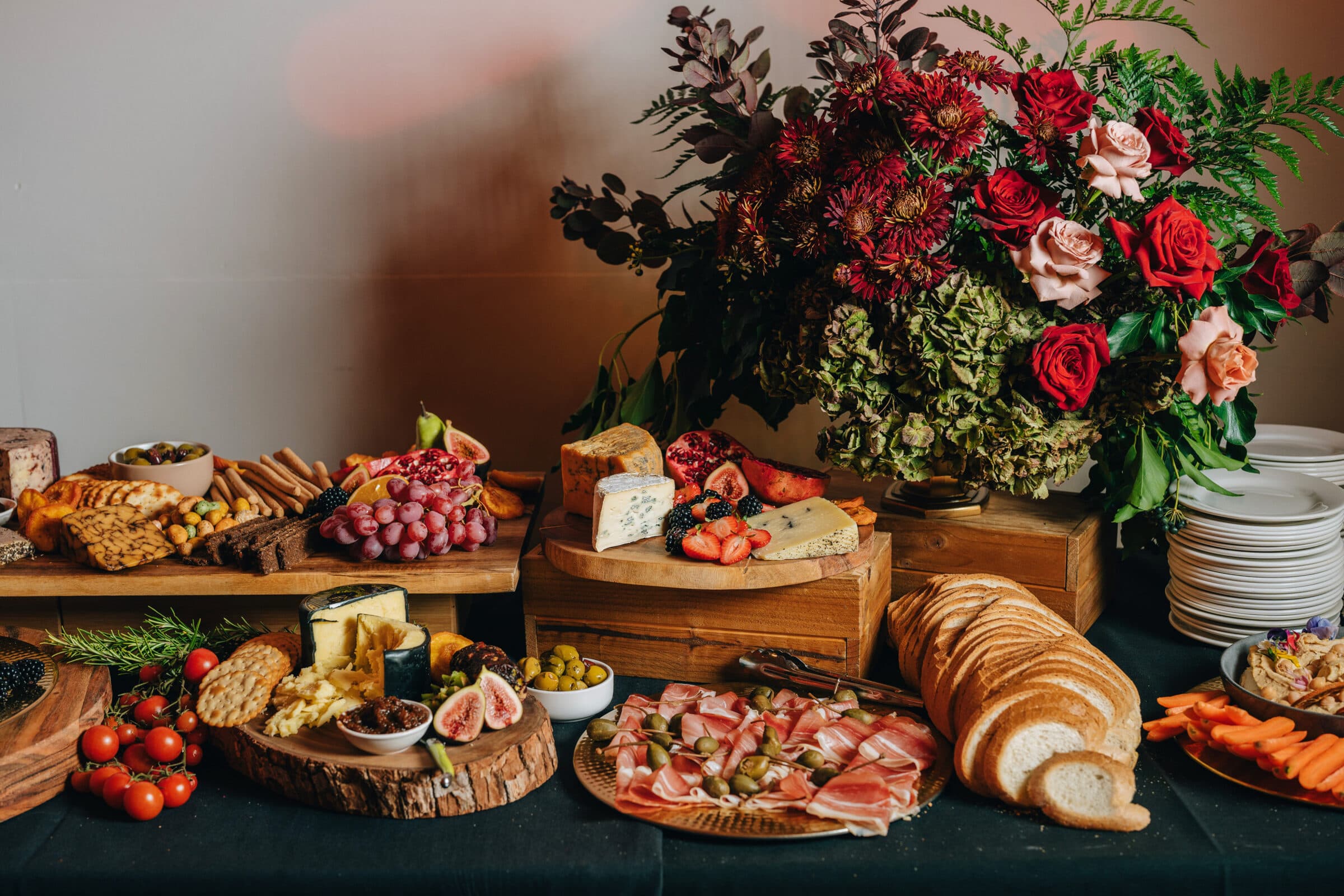 Lavish grazing table with charcuterie, cheeses, figs, and a centrepiece of red and blush roses for a Barossa Valley wedding